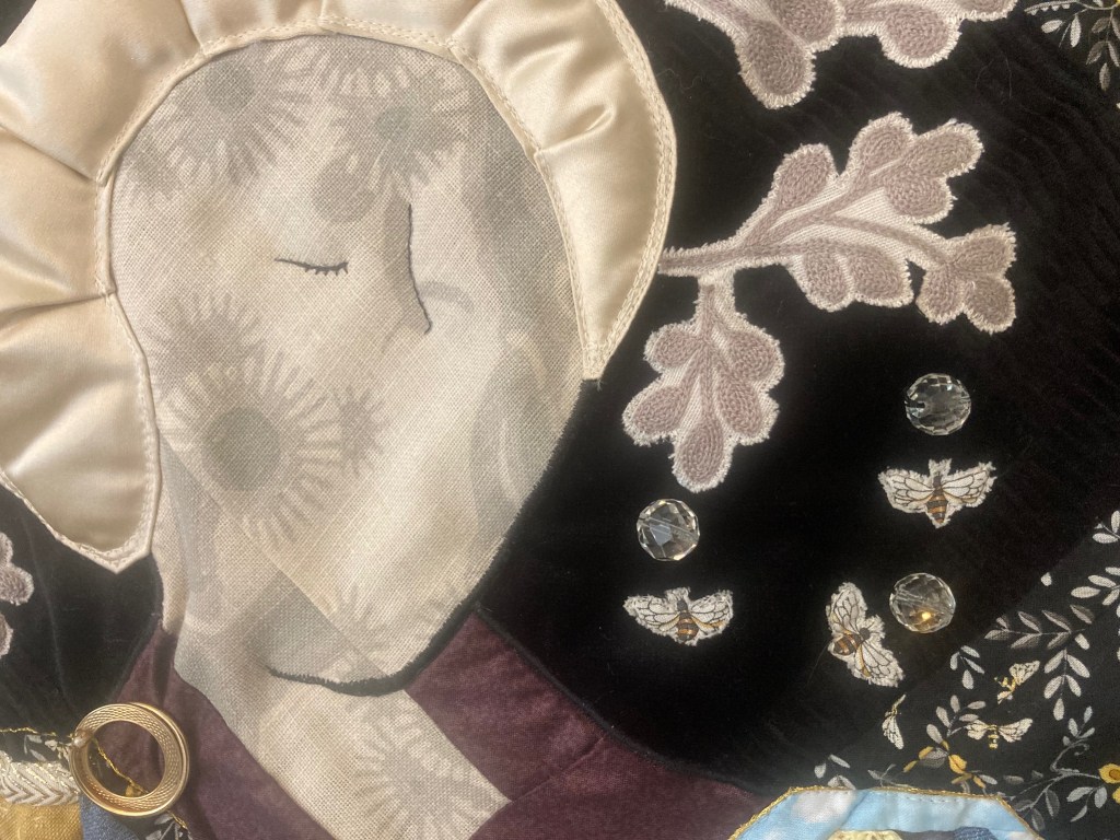 Image shows a detail of a figurative quilt embellished with crystal beads and appliqued bees